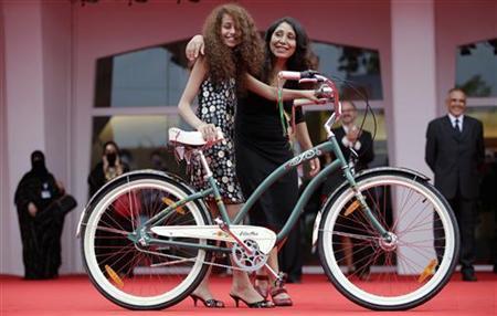 Saudi Arabian director Haifaa al-Mansour and actress Waad Mohammed pose with a bicycle on the red carpet during the premiere screening of "Wadjda" during the 69th Venice Film Festival in Venice
